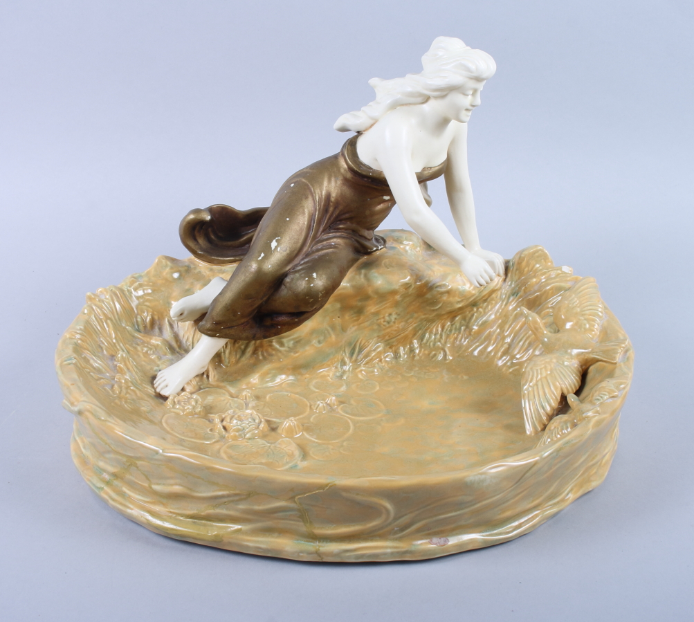 A Honenstein Art Nouveau table centre, formed as a girl sitting by a pond feeding a duck (damages