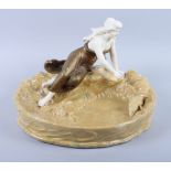 A Honenstein Art Nouveau table centre, formed as a girl sitting by a pond feeding a duck (damages