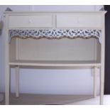 A painted side cabinet, fitted gallery top over two drawers and shelf, on square tapered supports,