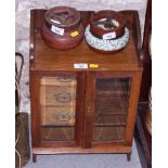 A smoker's oak cabinet, fitted three drawers enclosed two glazed doors, two tobacco jars, two clay