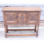 A carved oak side cabinet enclosed two doors, on turned and stretchered supports, 30" wide, a carved