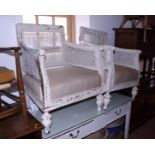 A pair of white painted double bergere armchairs with calico seats, on turned supports