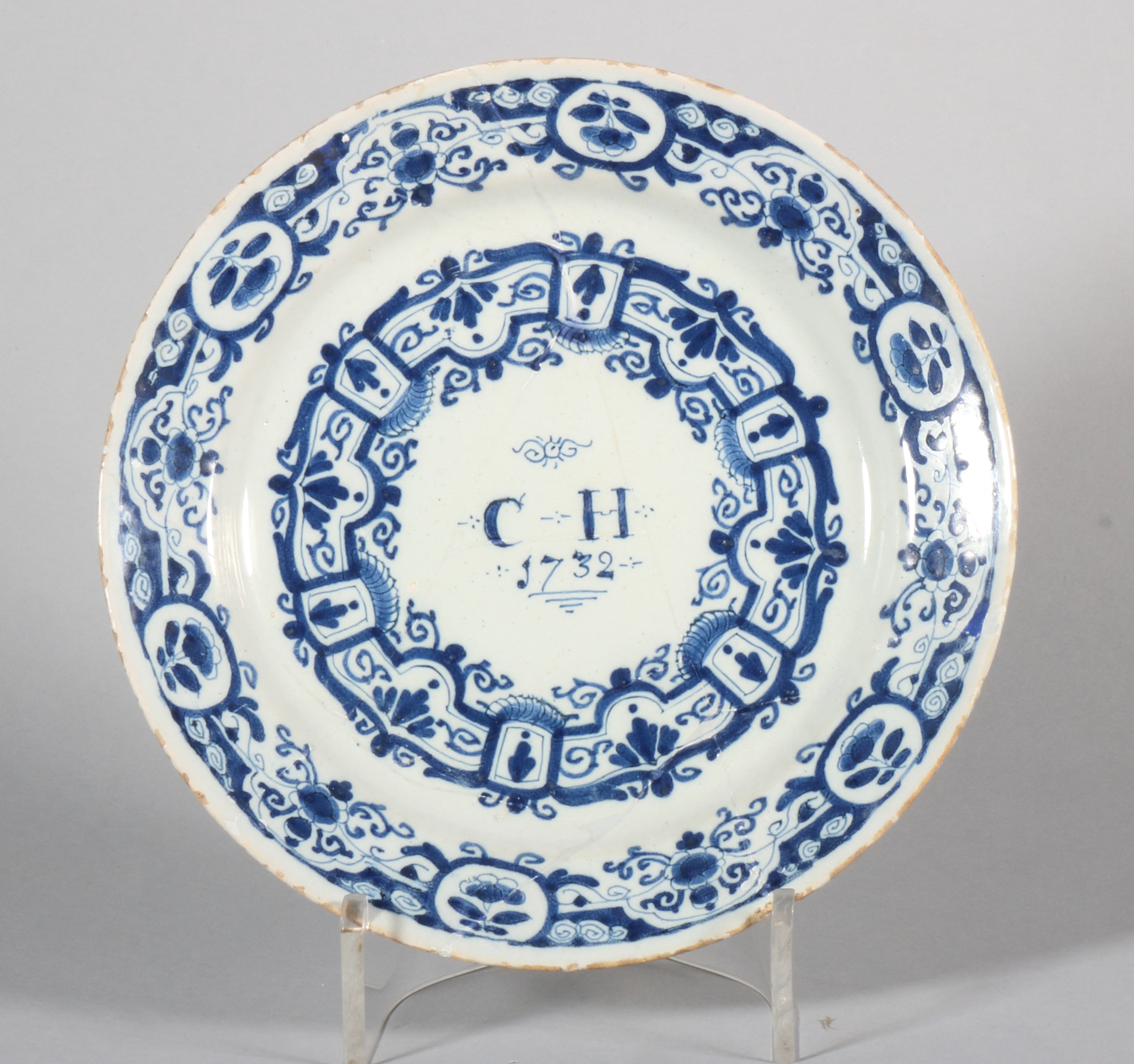 An early 18th century Bristol delft plate with swag and scroll decoration, inscribed monogram "