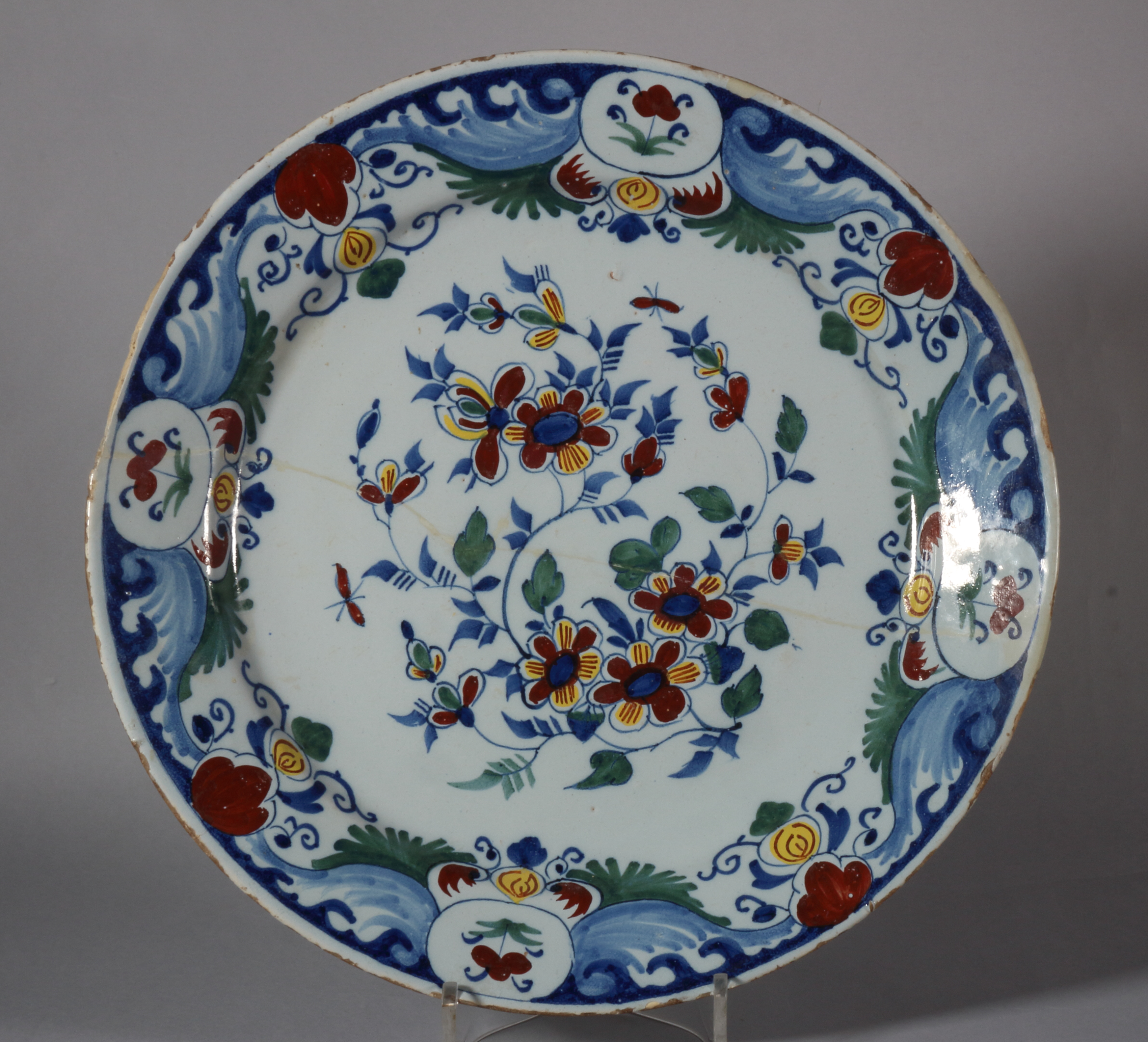 An 18th century Bristol delft charger with spray of flowers and insect decoration, monogram "WP" for