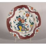 An 18th century London delft polychrome plate with reserved chinoiserie panels on a powdered