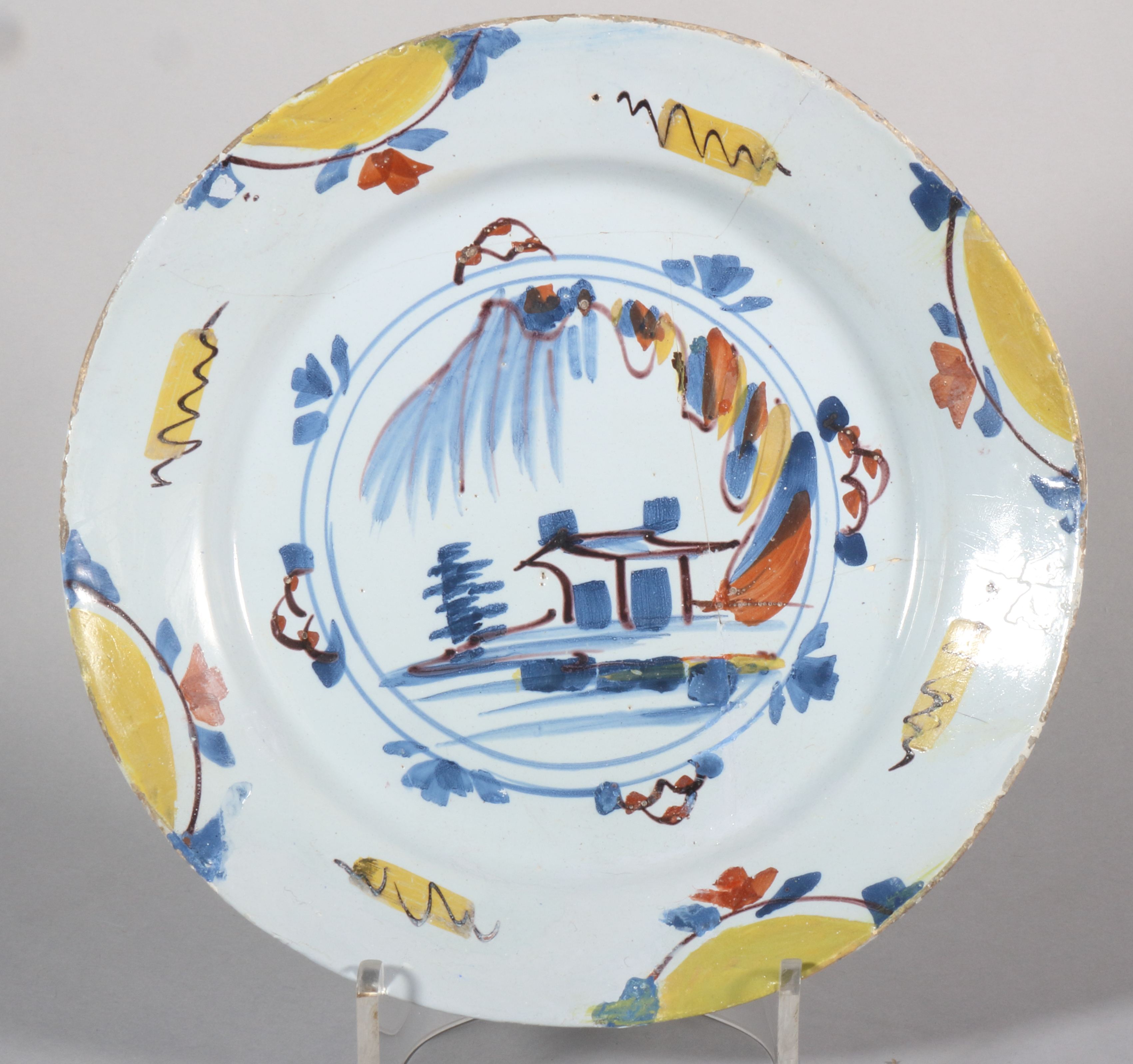 An 18th century English delft plate with polychrome landscape centre and border decoration, 8 7/8"