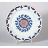 An early 18th century English delft plate with central manganese spiral and leaf decoration, 8 7/