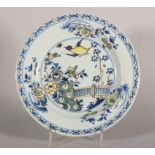 An 18th century London delft polychrome plate with bird, root and fence decoration, 9" dia (