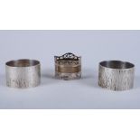 A pair of contemporary bark effect silver napkin rings and one other silver napkin ring, 3.1oz
