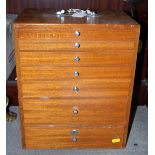 A dentist's mid 20th century walnut cabinet of seven graduated drawers, complete with accessories