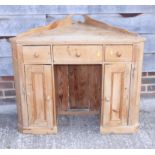 A waxed pine corner dressing table, fitted two small drawers and cupboards