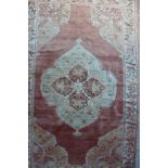 A Persian rug with central medallion on a faded salmon ground, 82" x 53" approx