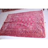 A Bokhara rug with sixteen guls on a red ground, multi-bordered in shades of red, blue, brown and