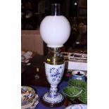 A late Victorian milk glass oil lamp, hand painted with floral decoration, on a mahogany circular