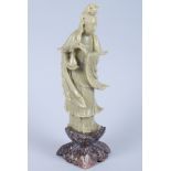 A Chinese carved soapstone figure of Kuanyin holding a peach standing on a carved base, 10" high,