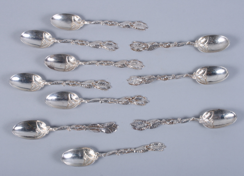 A matched set of ten Victorian silver teaspoons with leaf and flower decorated handles and crest