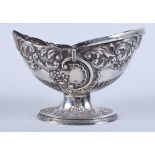 A late Victorian silver bonbon dish with embossed scroll and floral decoration, on oval pedestal