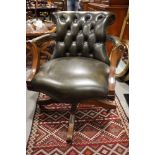A polished as mahogany oak elbow chair, button upholstered in a green leather