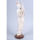 A Japanese Meiji period carved ivory figure of a woman holding a flower, on a pierced hardwood