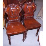 A pair of early Victorian carved mahogany shield back hall chairs, with panel seats