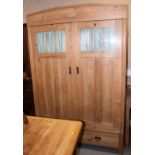 A Continental stripped pine wardrobe enclosed two glazed panel doors over two drawers, 51" wide
