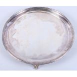 A late 20th century circular silver salver with reeded rim, on scroll feet, 24.6oz troy