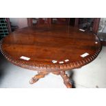 A mid 19th century rosewood circular table with dental rim, on central carved column with four