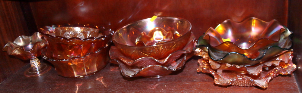 A collection of carnival glass dishes, including a blue/green dish decorated leaves and berries