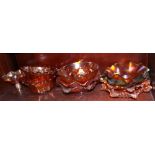 A collection of carnival glass dishes, including a blue/green dish decorated leaves and berries