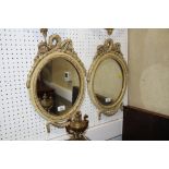 A pair oval wall mirrors with ribbon crests