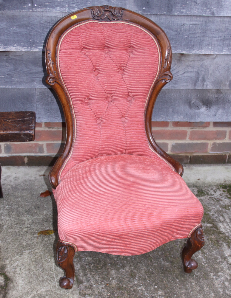 A Victorian carved walnut showframe low seat chair, button upholstered in a salmon ribbed fabric, on