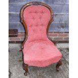A Victorian carved walnut showframe low seat chair, button upholstered in a salmon ribbed fabric, on