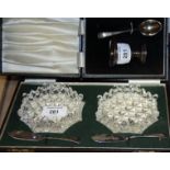 A silver egg cup and spoon set, in case, a pair of cut glass butter dishes with silver butter