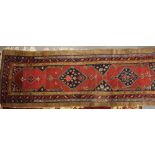 A Persian tribal runner with two hexagonal blue guls on a red ground, 94" x 33" approx (slight