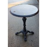 A cast iron table with hardwood top, on central column