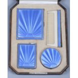 A George V silver four-piece and blue guilloche enamel vanity set, comprising a compact, a comb, a