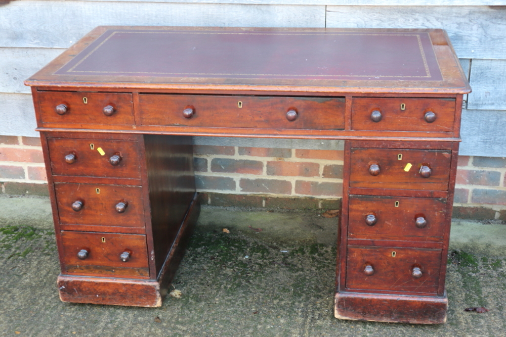 A mahogany double pedestal desk with red leather tooled lined top, fitted nine drawers, on block