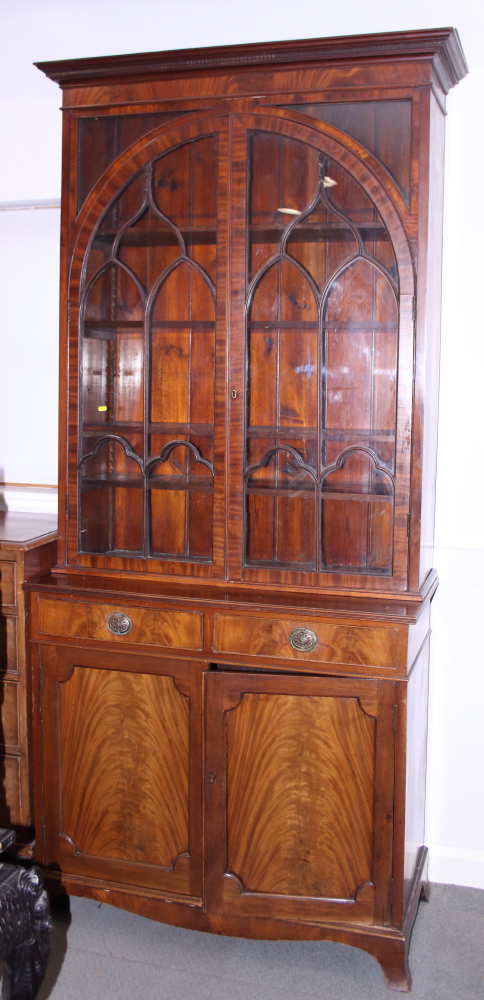 A mid 19th century mahogany book case, the upper section with Gothic lattice glazed arch top doors