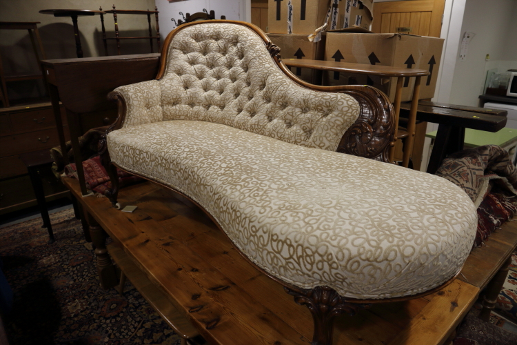 A mid Victorian carved walnut showframe chaise longue with serpentine seat rail, on cabriole