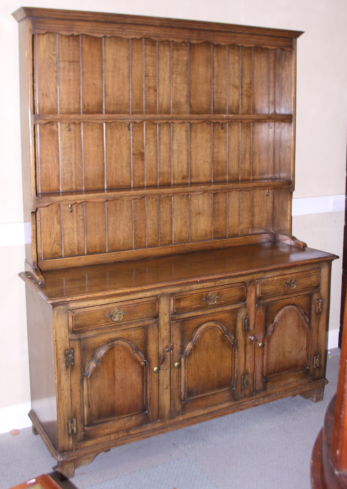 An oak dresser with plate shelves over three drawers and cupboards, on stile supports, 60" wide x