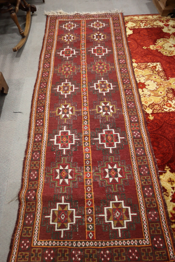 A Sumac type flat weave runner with eighteen hooked medallions on a plum ground and multi-borders,