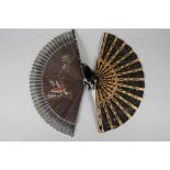 A black lace fan with gilt decorated guards, 8" long, and a butterfly decorated fan with lacquered