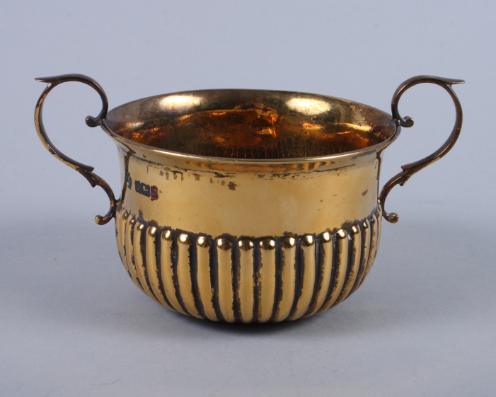 A George V silver gilt two-handled porringer with half-reeded body and "S" scroll handles, 4.4oz