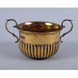 A George V silver gilt two-handled porringer with half-reeded body and "S" scroll handles, 4.4oz