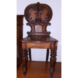 A late 19th century carved oak hall chair with shield back, on turned supports