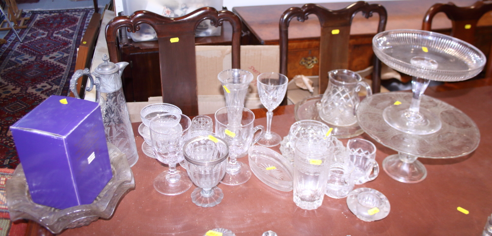 A collection of cut, etched and moulded glassware, including glasses, cake stands, a claret jug,