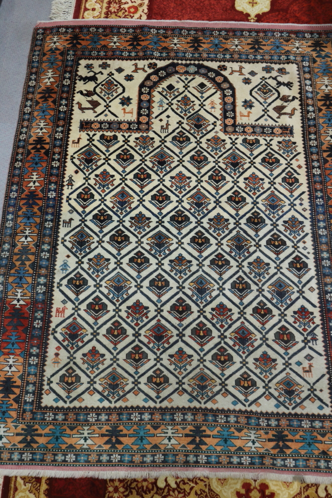 A Persian prayer rug with all-over lattice and florette design on a light ground, with figures and