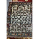 A Persian prayer rug with all-over lattice and florette design on a light ground, with figures and