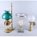 A brass oil lamp style table lamp, another similar, and a candle stand with storm shade