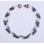 An Art Deco sapphire and baroque pearl three-strand necklace with a sapphire and white metal "bow"